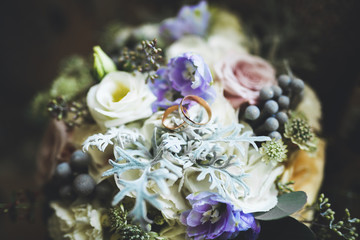 Beautiful toned picture with wedding rings against the background of a bouquet of flowers