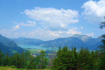 Lake called Wolfgangsee in Austria with mountains in the background and clouds on the sky and grass in the front