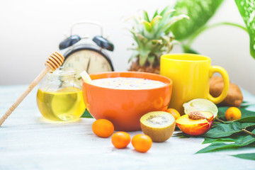 morning coffe Breakfast muesli, fruit, peaches, honey and pineapple on a light background with green leaves Awakening with an alarm clock Healthy breakfast freshness Closeup