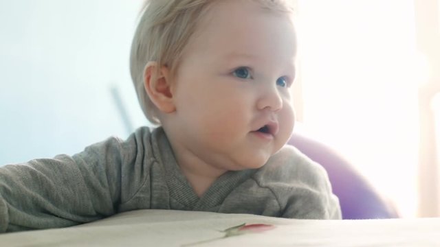 closeup portrait of happy smiling child with big beautiful blue eyes on white sunny background inside chubby cheeks excited baby boy ten months old playful cheerful infant proud of standing himself