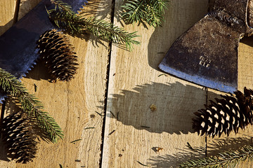 A branch of spruce, pine cone and an ax on a wooden background