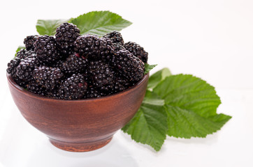 Black raspberries in a clay plate. Black raspberry and leaves.