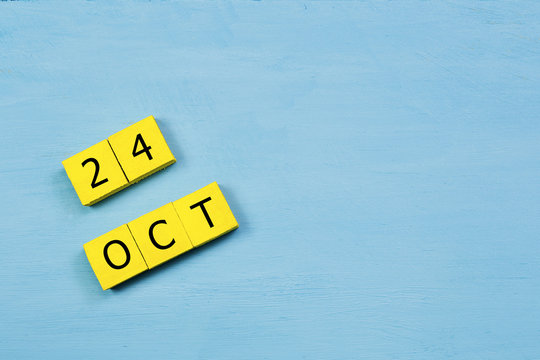 OCT 24, yellow cube calendar on blue wooden surface with copy space
