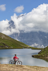 nice and ever young senior woman riding her e-mountainbike below the Eiger northface, Jungfrauregion, Switzerland