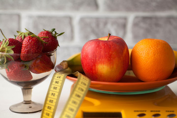 Healthy living or Diet concept. Fruits with measuring tape and a weight scale. Fresh strawberry. Summer time.