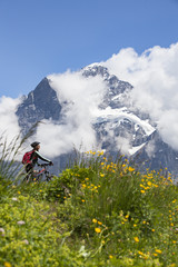 nice and ever young senior woman riding her e-mountainbike below the Eiger northface, Jungfrauregion, Switzerland