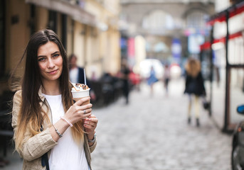 Young stylish woman drinking coffee to go in a city street