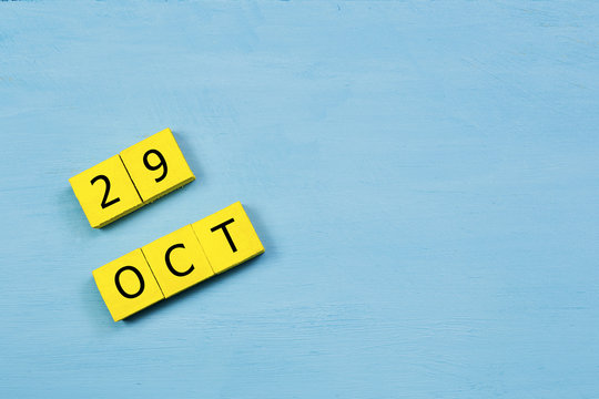 OCT 29, yellow cube calendar on blue wooden surface with copy space