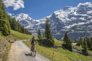 Fototapeta premium nice and ever young senior woman riding her e-mountainbike below the Eiger northface, Jungfrauregion, Switzerland