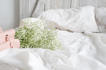 Soft home interior. Bed, white and pink bedspreads, old wood headboard. Cozy mornung