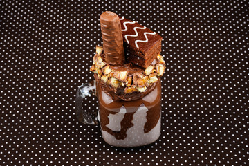 Chocolate extreme milkshake with brownie cake, chocolate paste and sweets. Crazy freakshake food trend. Copy space
