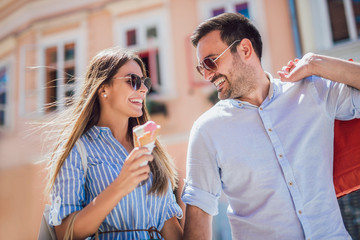 Happy couple having date and eating ice cream after shopping