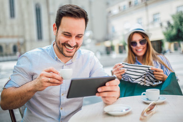 Beautiful loving couple sitting in a cafe enjoying in coffee and conversation after shopping, using digital tablet