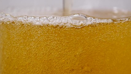 Pouring light beer into glass close up, slow motion