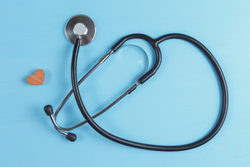 Stethoscope and wooden heart on blue background