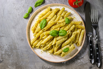 penne pasta with pesto sauce in plate on a wooden background. top view