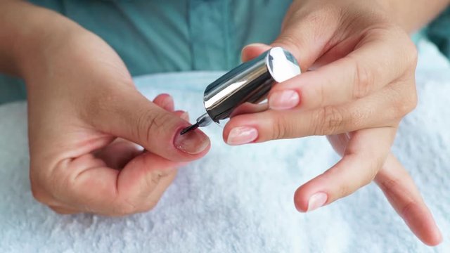Woman applying treatment nail lacquer while home manicure. Woman doing healing manicure close up. Home manicure, treatment and nail care concept.