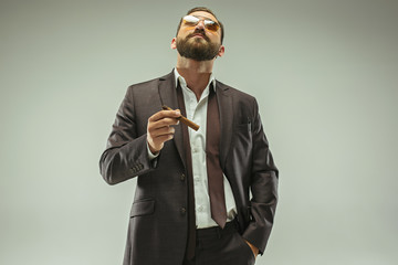 The barded man in a suit holding cigar