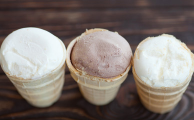 Homemade chocolate and vanilla ice cream in waffle cups on wooden background. Healthy summer food concept with copy space.