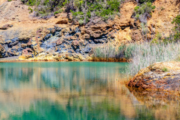 Very colorful lake and rocks nearby a mine on the island of Elba in the Tuscany, Italy. Surface Mineral Concomitant Iron Ore, Industrial Iron Ore Mining