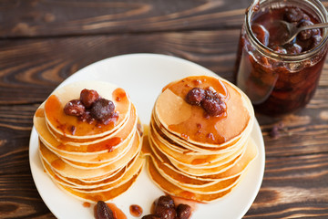 Delicious pancakes on wooden table with strawberry jam