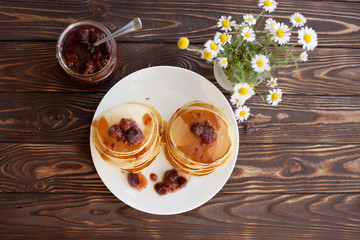 Well baked pancakes are topped with maple syrup for an extra taste. A bite of butter is melting on top of the stack. These pancakes are the one of American meals.