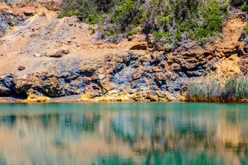 Very colorful lake and rocks nearby a mine on the island of Elba in the Tuscany, Italy. Surface Mineral Concomitant Iron Ore, Industrial Iron Ore Mining