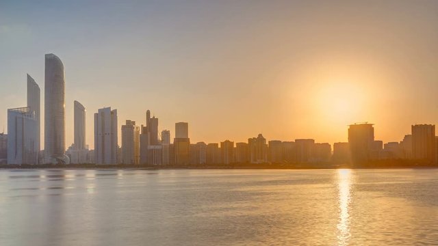 Abu Dhabi city skyline on sunrise time with water reflection timelapse.