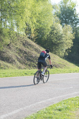 Back of a cyclist with a backpack while riding in the city on a bike. Man in sportswear and a helmet rides the city park.