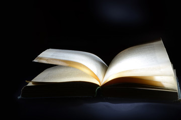 Old open book on a black background