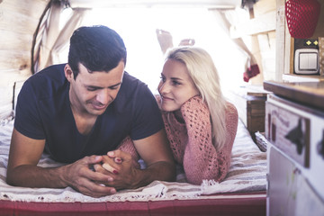 Fototapeta premium caucasian couple in love and romantic scene inside an old vintage camper ready to travel and have a vacation together with happiness and joy. blonde beautiful model lay down and stay nice