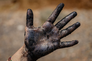 A hand full of black mineral sand from the beach on the island of Elba in the Tuscany, Italy. The sand is reflecting in the sun and has beautiful colors.