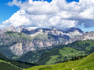 Fototapeta na wymiar Picturesque July layered Alpine view from the Sella Pass in the Dolomites with big cumulus clouds, in South Tyrol, Italy