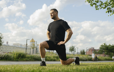 Young attractive man doing lunge outdoor.