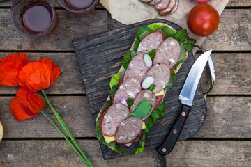 Sandwich with sausage slices, tomato and lettuce, top view