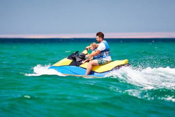 happy, excited family, father and son having fun on jet ski at summer vacation