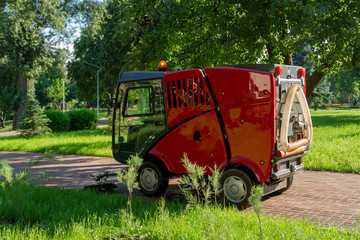 The red machine for washing sidewalks in the park washes the paths with brushes.
