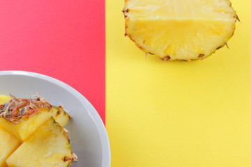 Pieces of pineapple on a white plate, chopped pineapple on a red yellow background, a salad of tropical fruits for breakfast, vegetarian food in the style of pop art, copy space