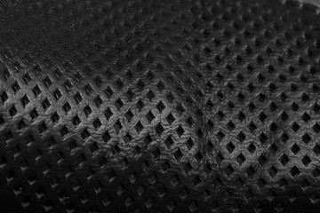 Natural black leather with perforation in form of the squares. Abstract background