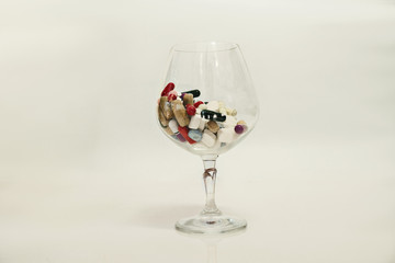 pills in wine glass on white background