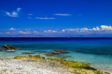 Fototapeta na wymiar Picturesque summer beach, pebbles in the surf line on a beautiful turquoise sea, Rhodes, Greece