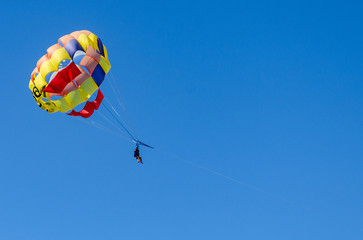 A couple having a ride with a colorful parasail towed by a boat at the coast of Tenerife, Canary Islands, Spain