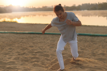 Athletic capoeira performer making movements on the beach