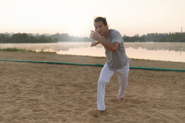 Athletic capoeira performer making movements on the beach