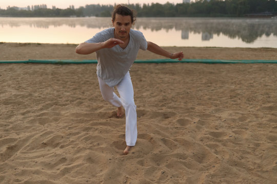 Athletic capoeira performer making movements on the beach