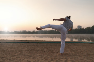 Fototapeta na wymiar Capoeira performer near the lake in the parc