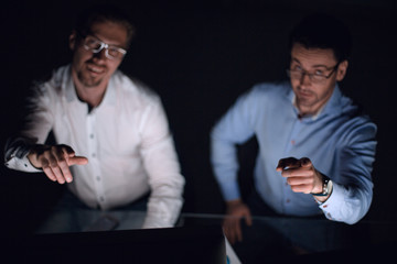 close up.two colleagues sitting at their Desk and pointing at you