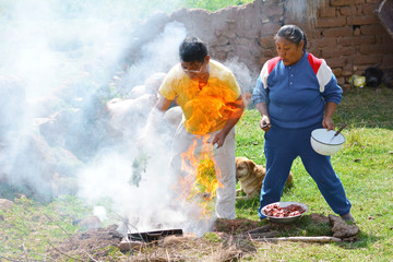 Native american man and woman cooking in the countryside with very dangerous flames.