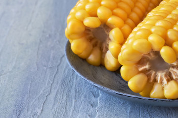 Closeup on two ends of boiled corn on the cob on rustic neutral background