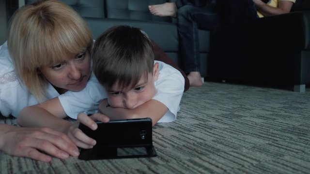 Happy family mom, dad and son watching movies and playing games on phones and laptops